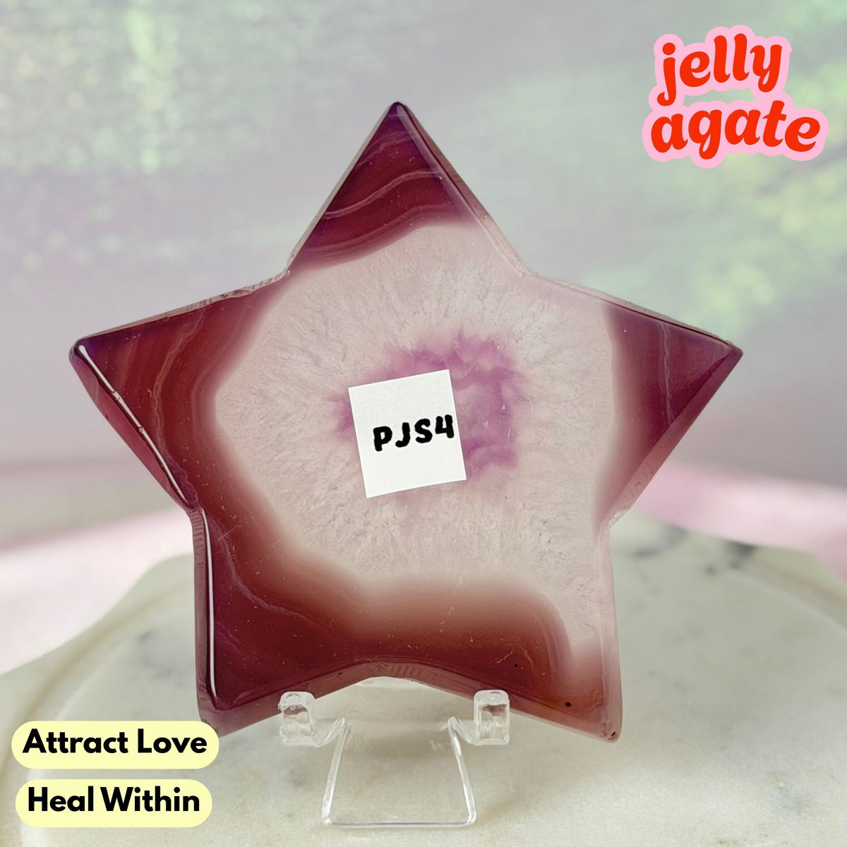 A star-shaped jelly agate crystal display piece on a clear acrylic stand, featuring a marbled pattern of deep burgundy and pale pinkish-white. The image includes text overlays reading 'jelly agate', 'Attract Love', and 'Heal Within', with a small white label in the center reading 'PJS4'.