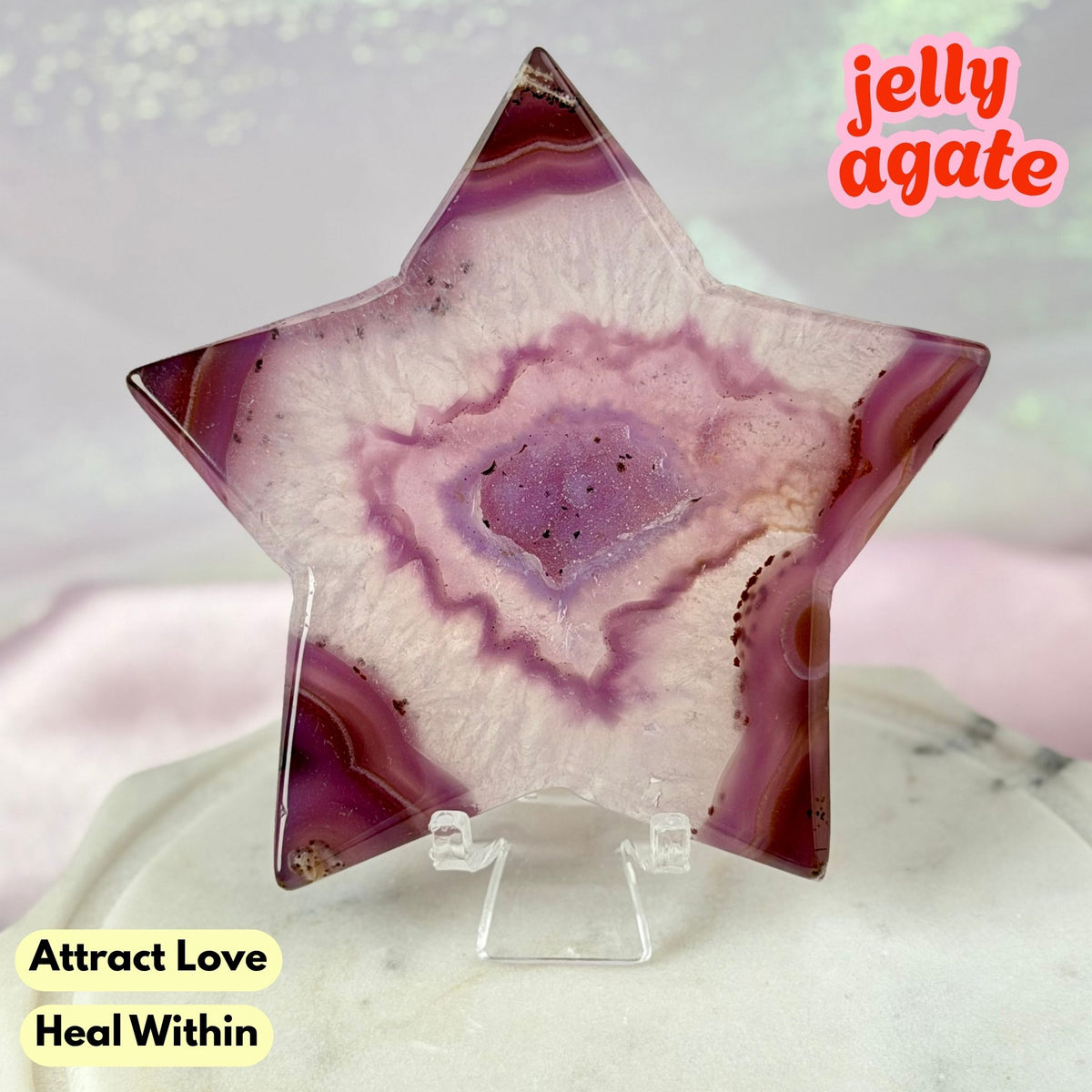 A star-shaped polished jelly agate crystal displayed on a clear acrylic stand. The agate features a swirling pattern of purple, pink, and white, with a small white label in the center reading 'PJS6'.