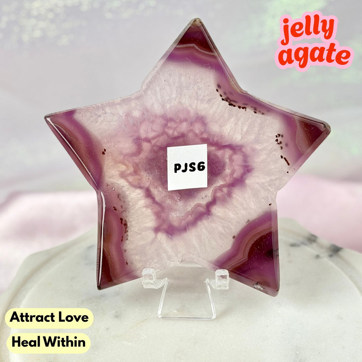 A star-shaped polished jelly agate crystal displayed on a clear acrylic stand. The agate features a swirling pattern of purple, pink, and white, with a small white label in the center reading 'PJS6'.