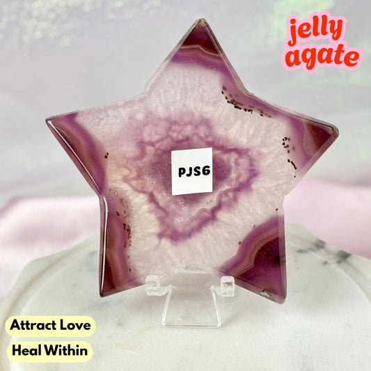 A star-shaped polished jelly agate crystal displayed on a clear acrylic stand. The agate features a swirling pattern of purple, pink, and white, with a small white label in the center reading 'PJS6'.