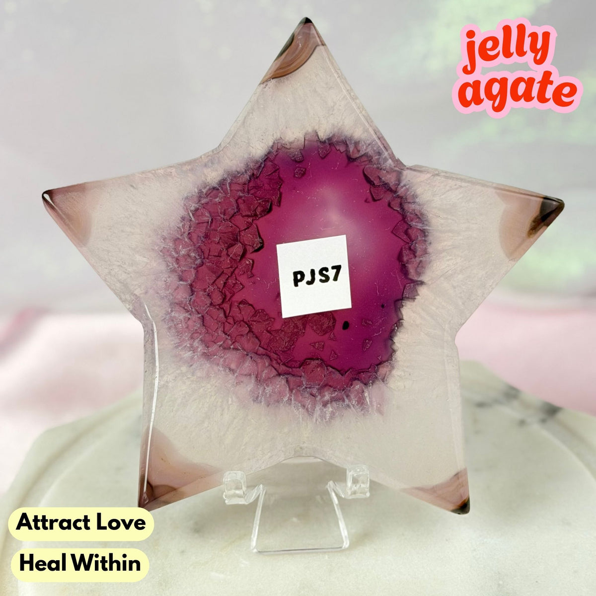 A star-shaped clear resin candle holder with a magenta-purple agate geode center, displayed on a clear acrylic stand. The text 'jelly agate' is in the top right, and 'Attract Love Heal Within' is in the bottom left.