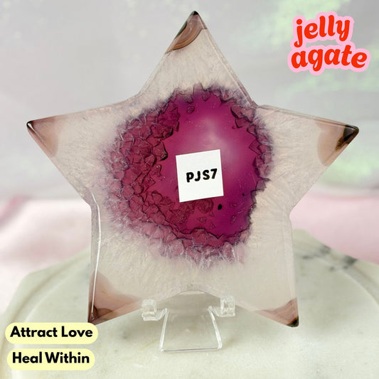 A star-shaped clear resin candle holder with a magenta-purple agate geode center, displayed on a clear acrylic stand. The text 'jelly agate' is in the top right, and 'Attract Love Heal Within' is in the bottom left.