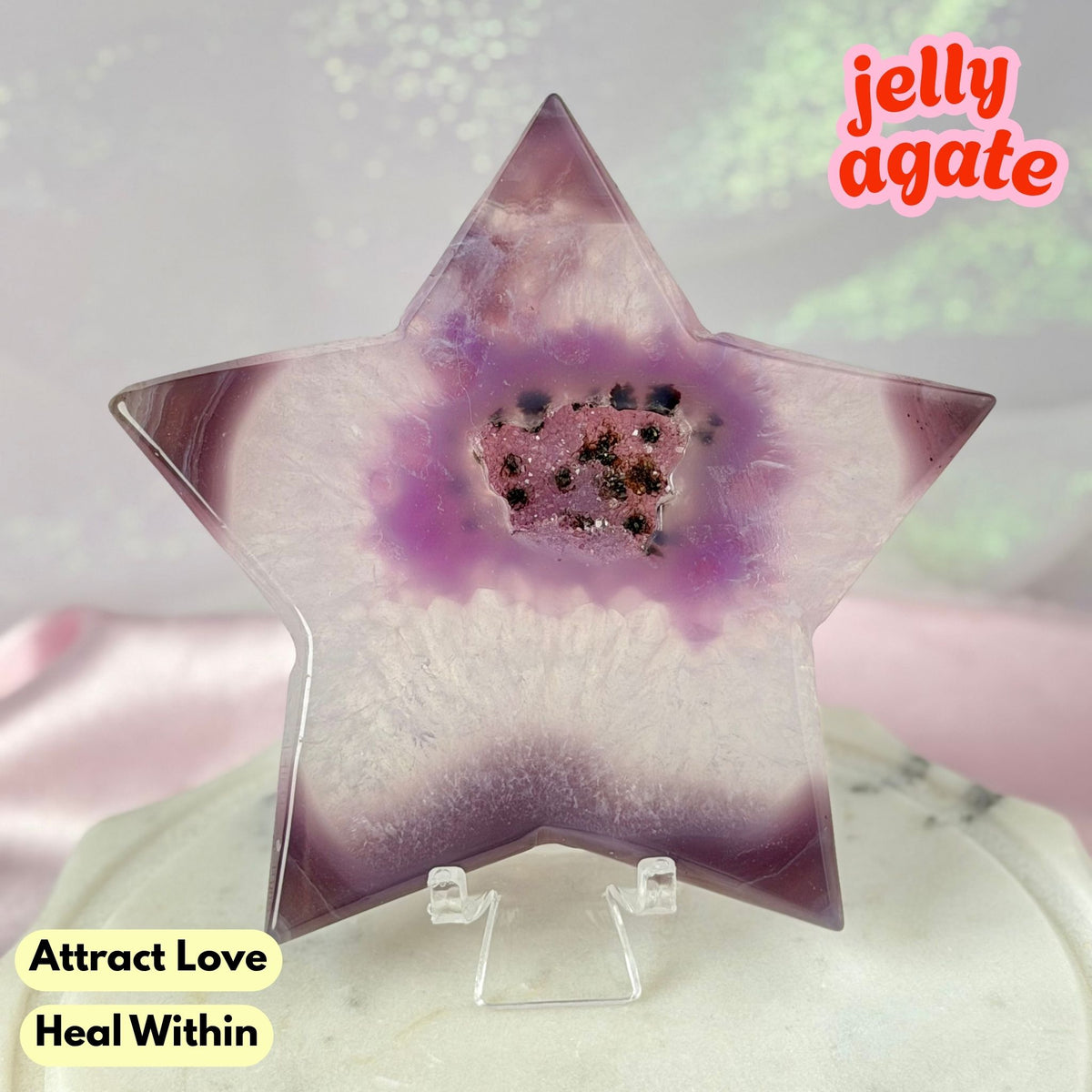 A star-shaped polished jelly agate crystal displayed on a clear acrylic stand. The agate features a gradient from light lavender to deep purple with a central cluster of small black and pinkish-brown inclusions.