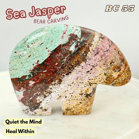 A polished sea jasper bear carving with multicolored natural stone patterns, featuring a mint green top, red and brown stripes, and pink and tan lower sections. Text overlays read 'Sea Jasper', 'BEAR CARVING', 'BC 55', and 'Quiet the Mind Heal Within'.