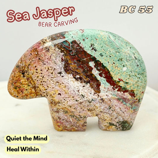 A carved sea Jasper bear figurine with a multicolored natural pattern of mint green, pink, brown, and gold, displayed on a light marble surface with text overlays.